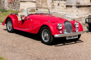 Framlinghan, England - July 10, 2015: Red replica of a Morgan veteran sports car with the hood down outside a church in Framlingham, Suffolk,