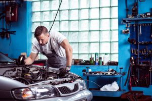 Young strong car mechanic at work in shop